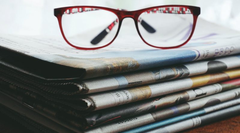 red framed eyeglasses on newspapers